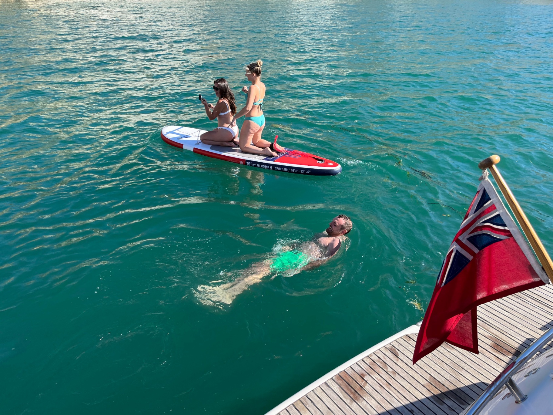 Swimmers and paddleboarders enjoying the clear turquoise waters of the Solent from a charter boat